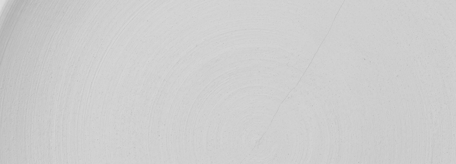 Unglazed fired clay thrown on a wheel: concentric throwing rings across the surface, with one hairline crack running clean through them.